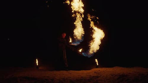 Cascadeur professionnel exécutant un spectacle de feu spectaculaire avec des brûleurs à gaz à l'extérieur pendant la nuit