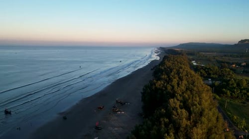 Aerial View of a Calm Ocean with Morning Light Filtering Through Trees—Tranquil Coastal Sunrise