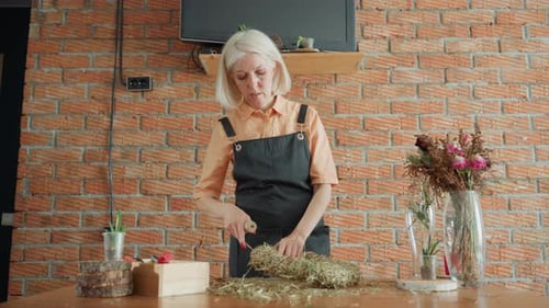 Woman Making Floral Decoration at Table Indoors