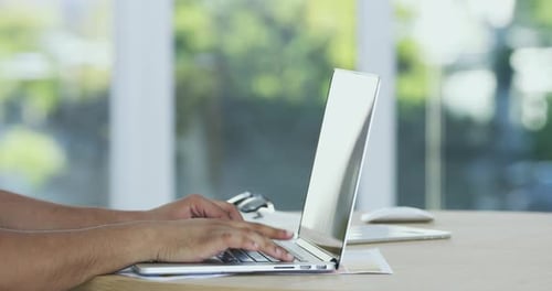 4k video of an unidentifiable businessperson working on a laptop in an office