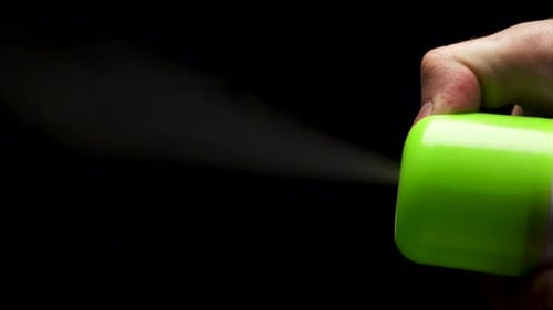 Grüner Nebel aus einer Flasche vor dunklem Hintergrund mit künstlerischem Touch sprühen