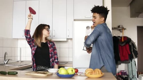 Young Adults Dancing in Kitchen with Utensils
