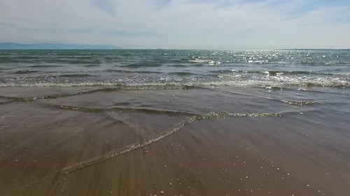 Waves Gently Coming onto Sandy Beach on Sunny Day
