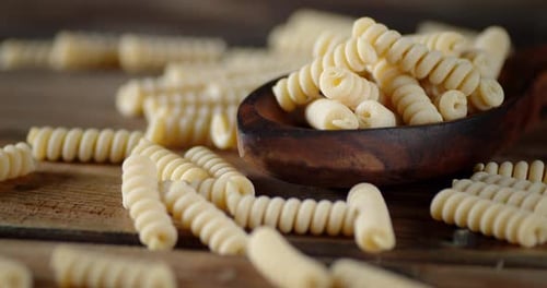 Les pâtes fusilli sèches sur la table et à la cuillère tournent lentement.