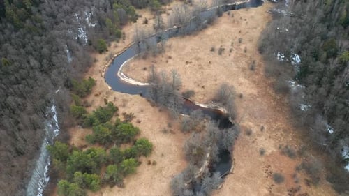 AERIAL: Curvy River Flows Across Forest in Early Spring in Eastern Europe