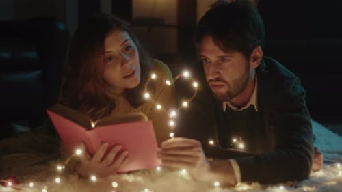 Romantic Couple Reading a Book by Fairy Lights
