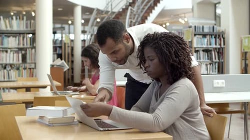 Adults Working Together on Laptop in Library