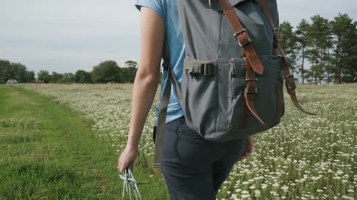 Woman Hikes Through Rural Field of Flowers