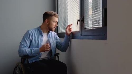 Sad Disabled Man Sitting in a Wheelchair Near the Window
