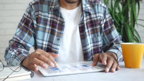 Junger Mann in lässiger Kleidung arbeitet zu Hause am digitalen Tablet