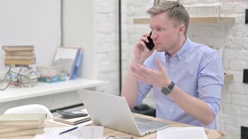 Frustrated Man Talking on Phone in Office