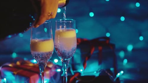El champán sale de la botella, dos flautas con un bokeh de vino espumoso parpadeando