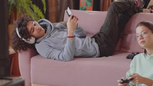 Teens Relaxing on Couch with Phone and Game