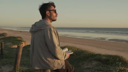 Mann liest im Sommer am Meer Buch