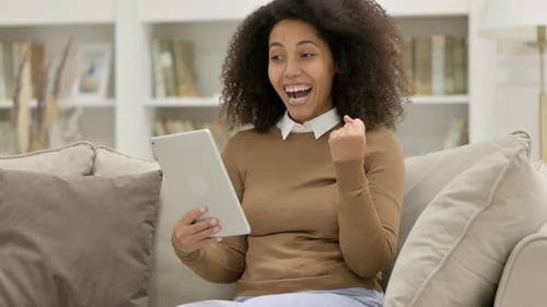 Excited Woman Celebrates Good News on Tablet