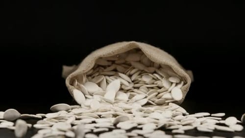SLOW MOTION: A Sac With Dried Pumpkin Seeds Fall On A Table