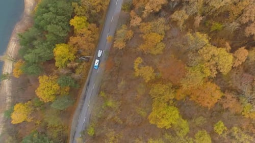 Drone Following Two SUV Towing Boats, Driving Near Lake on Forest Road