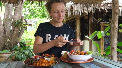 Young Woman Taking Photo Of Food With Phone In Healthy Vegan Restaurant Outdoors