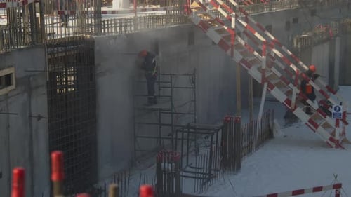 Baumeister schleift Wand auf Gerüsten auf der Baustelle