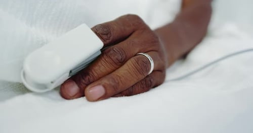 Primer plano de la pulsioximetría en la mano de un paciente masculino afroamericano en la sala del hospital