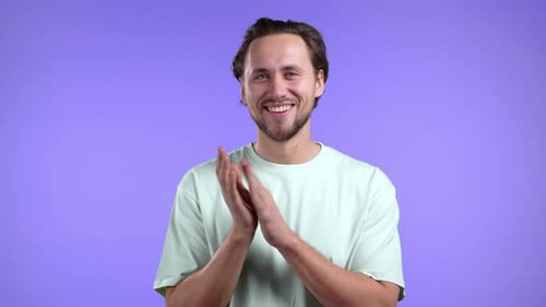 Lächelnder europäischer Mann applaudiert isoliert über violettem Studio-Hintergrund
