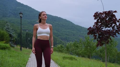 Young Sporty Woman is Walking in Park and Admiring Nature After Workout
