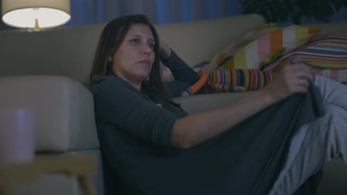 Belle femme seule adulte soirée à la maison assise sur le canapé et regardant la télévision