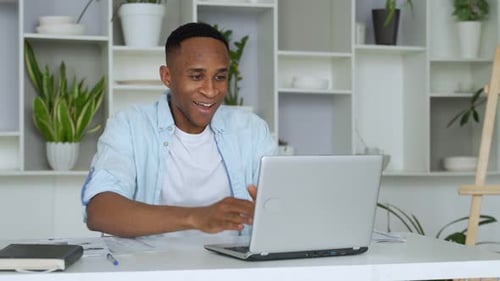 Excited Man Celebrating Success with Laptop at Desk