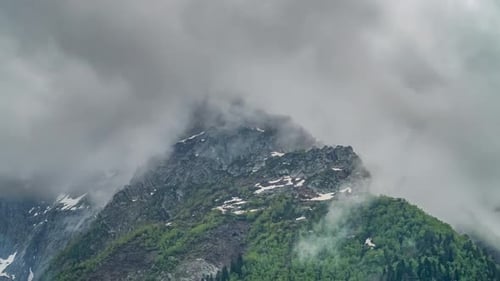 Caucasian Mountain Peak Covered with Snow Surrounded with Clouds and Flocks of Birds
