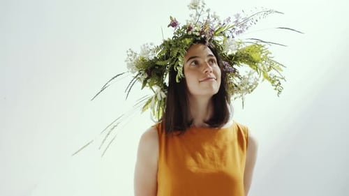 Studio Shot of Young Smiling Woman in Flower Wreath Posing for Camera
