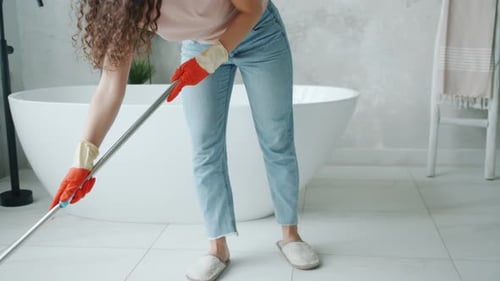 Tilt-up of Girl Washing Floor in Bathroom Using Modern Mop Busy with Housework