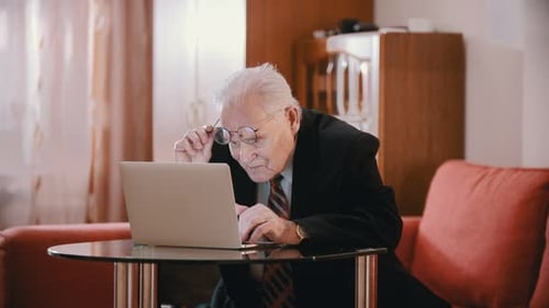Senior Man Works on Laptop at Home