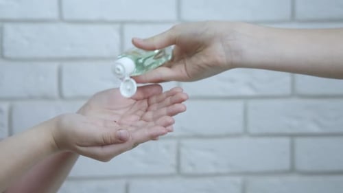 Child Receiving and Rubbing Sanitizer Into Hands
