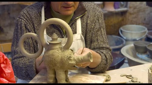 Craftsman Shaping Clay Teapot in Workshop