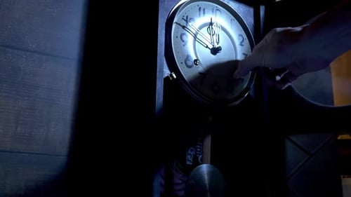 Close up of a male hand is using the key to the ancient pendulum clock