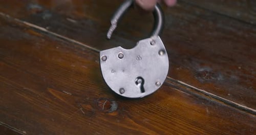 Pirate Picks Up Open Lock Lying on Wooden Floor in Cabin
