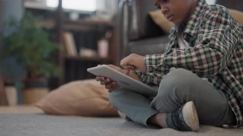 Boy Using Tablet Sitting on Floor Indoors