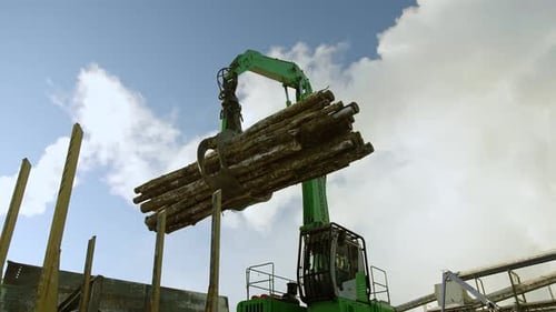 A Track Material Handler is Loading Logs Onto a Conveyor at the Factory