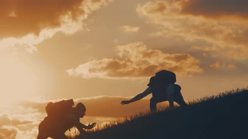 Silhouette of Helping Hand Between Two Climber. Two Hikers on Top of the Mountain