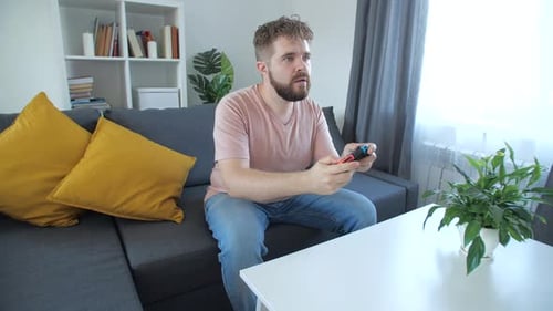 Man Playing Handheld Video Game Console on Couch