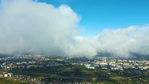 Aerial View From High Altitude of Distant City Covered with Puffy Cumulus Clouds Forming Before