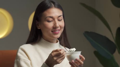 Woman Eating Yogurt From Bowl With Spoon