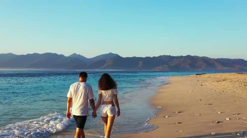 Couple walking by the sandy beach on a sunny day of Tropical Island in Philippines - surrounded by t