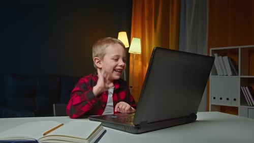 Smiling Boy Video Calling on Laptop at Desk
