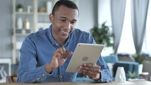 Young Adult Using Tablet at Table Indoors
