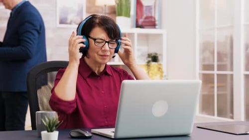 Mature Woman Working on Laptop with Headphones