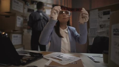 Woman Examines Film at Police Investigation Workplace