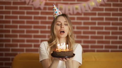 Woman Blowing Out Birthday Candles at Party