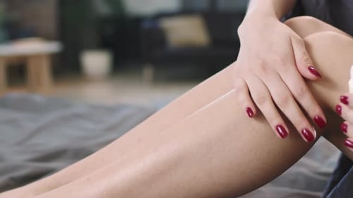 Woman Applying Body Lotion On Legs