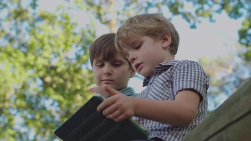 Two Young Boys Using Tablet Outdoors